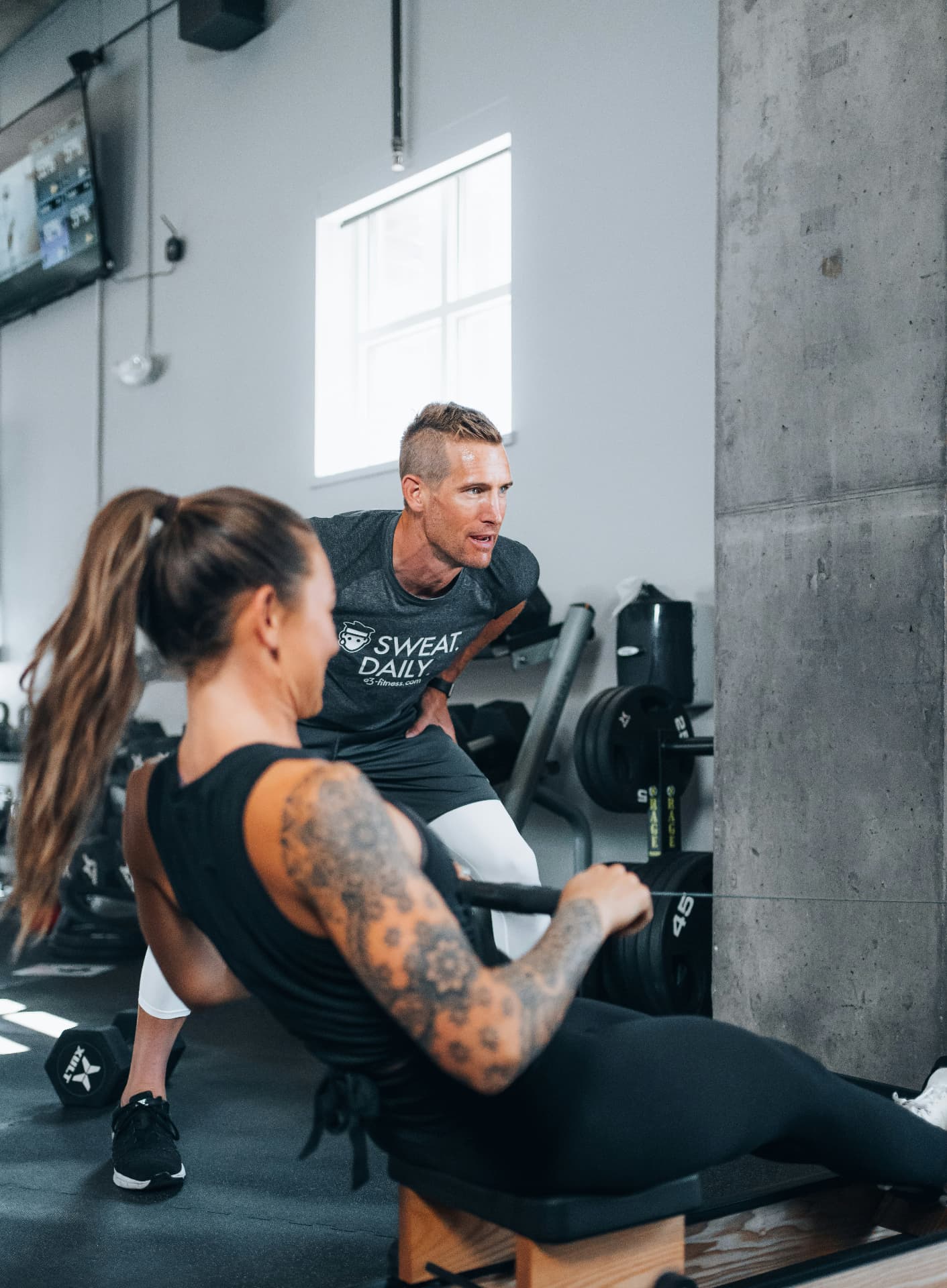 A personal trainer coaching a client through a seated row in a gym